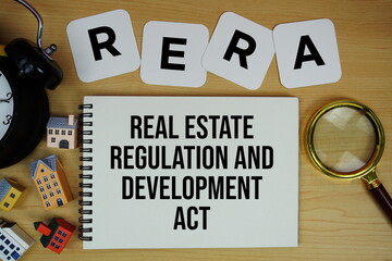 RERA Real Estate Regulation And Development Act text written on notepad with house model, alarm clock and magnifying glass on wooden background