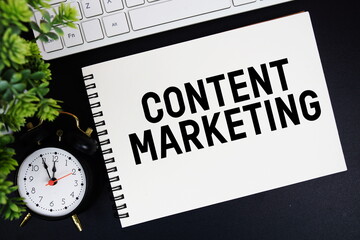 Content Marketing text written on notepad with keyboard and alarm clock on black background
