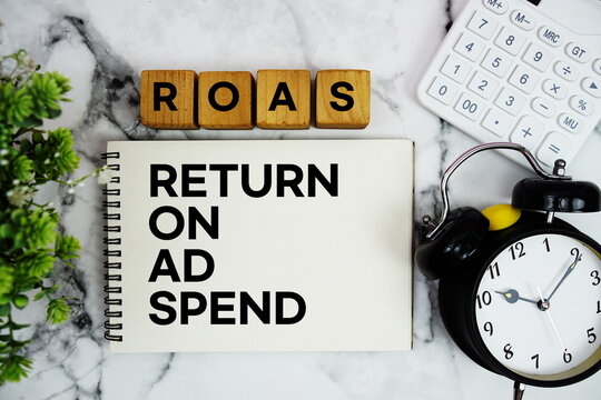 ROAS Return on Ad Spend text with calculator and alarm clock on marble background