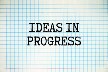 Ideas In Progress text written on white notebook sheet with grid