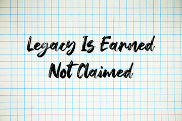 Legacy Is Earned Not Claimed text written on white notebook sheet with grid