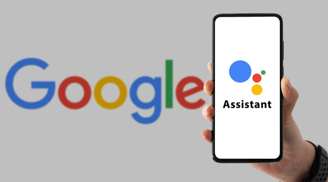 Hand holding smartphone with Google Assistant on screen