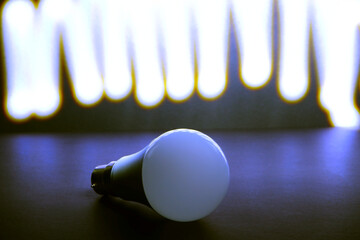 Energy efficient light bulb on dark surface with bright LED lights on background