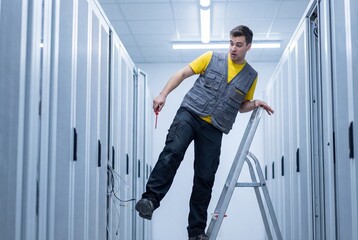 Shocked male technician losing balance and falling off a ladder in a modern data center server room