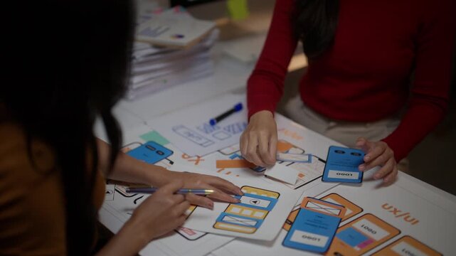 Team of female app developers working on a user interface and experience project, collaborating on the layout and wireframe for a new smartphone application