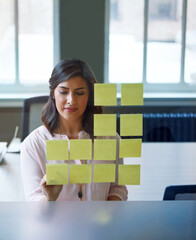 Woman, writing and glass with sticky note in office for planning, schedule and article ideas....