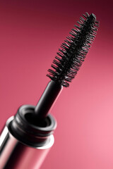 Naklejka premium Close-up image of a mascara wand against a pink background, ideal for beauty and makeup promotional content.