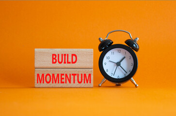Build momentum symbol. Wooden blocks with words Build momentum. Beautiful orange background with...