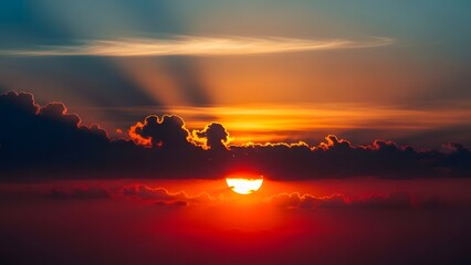 Sun setting behind dark clouds with radiant beams and vivid sky hues from orange to deep blue