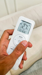 Air Conditioner Remote Control holding by male hand. Men, man. Close up view. High angle, above, flat lay. White. Vertical. Sstkvertical. Button, buttons. Cold temperature.