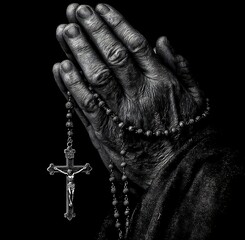 A person's hands clasped in prayer with a rosary and crucifix