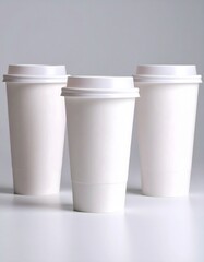 Three White Coffee Cups with Lids on a Light Gray Background