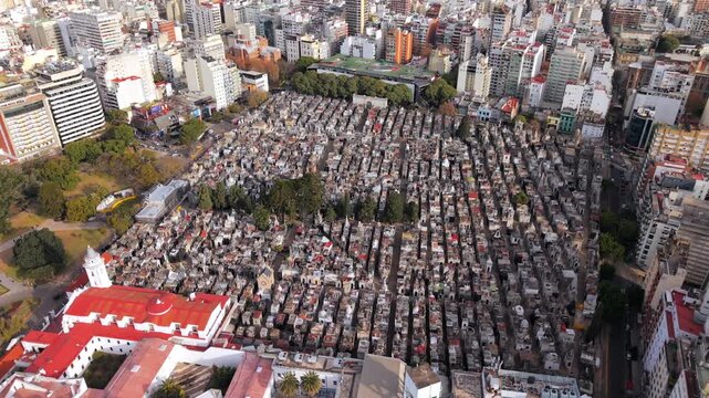Establishing shot contrasts the compact cemetery architecture with surrounding streets and mid‑rise buildings, emphasizing La Recoleta Cemetery as a monumental urban block in Buenos Aires, Argentina.