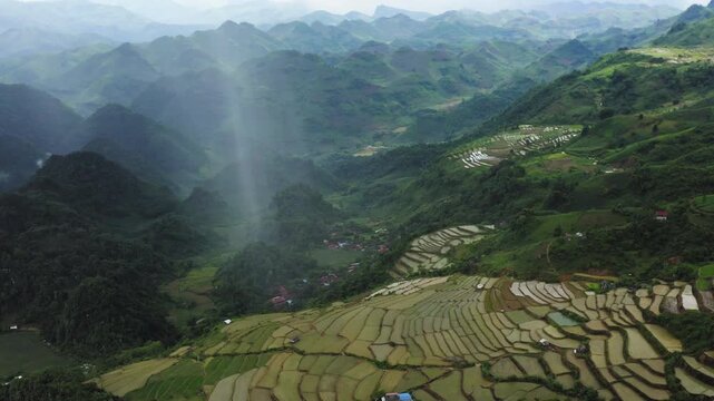 Drone camera tilt-up from the Mộc Ch&acirc;u tea hills, revealing the towering architecture of a cumulonimbus cloud and a localized rain shaft saturating the Sơn La highlands, Vietnam.