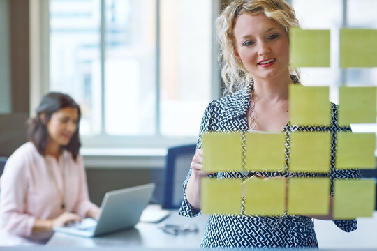 Woman, meeting and sticky note on glass wall for schedule, project management or task delegation. Marketing team, mindmap or planning in office for workflow, advertising campaign or business timeline