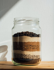 ガラス瓶の中で重なる土の層と地層