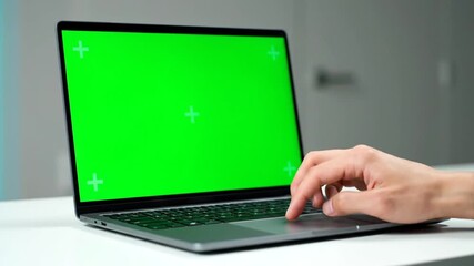 Person using laptop computer with green screen display