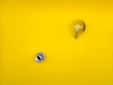 Tungsten light bulb lamp. Non-working light bulb, broken light bulb. Concept of light and dark, idea, electricity copy space, flay lay, top view yellow background. High quality - Powered by Adobe