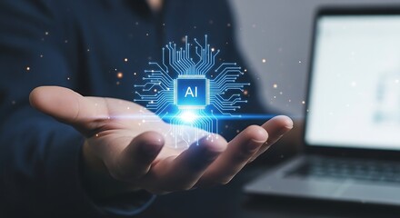 Artificial intelligence chip glowing with ai text in the center, held in a persons open palm with a laptop in the background, symbolizing future technology and innovation