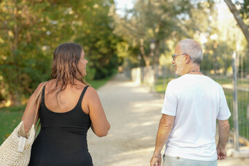 Obraz premium A woman and a man are walking together on a path. The woman is carrying a handbag