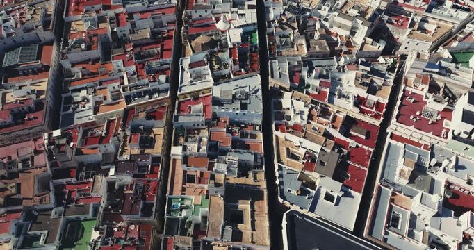 Tilting up reveal aerial drone shot of C&aacute;diz residential rooftops and dense urban neighbourhood, historic old town housing patterns, coastal Spanish city architecture. Cinematic grading of the skyline
