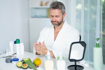 Fototapeta premium Facial cream for male skin. Man 40s applying facial cream for a beauty skincare routine. Facial beauty and rejuvenation for male. Facial morning routine. Man skincare concept.