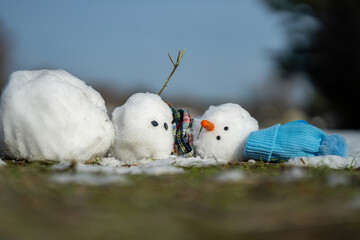 Snowman melting in warm winter or spring weather. Melted snowman as a symbol of climate change. Winter and spring seasons change. Melting snowman with puddles around it. From winter to spring.