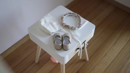 Infant shoes bonnet and floral headband placed on stool indoors