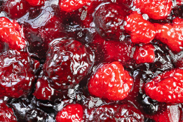Colorful fruit glaze, Glossy berry topping with sheen, Vivid raspberry layer with textured seeds and shine, Bright red fruit sauce with glossy finish and seed details present © beholdereye