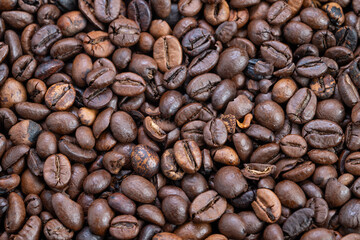 Obraz premium Closeup dark espresso coffee beans with oily sheen and deep brown color, tight composition emphasizing intensity and bold flavor profile for cafe and social media use