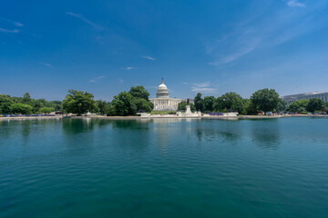 Capitol in Washington, DC. Capitol across the reflecting pool. Washington D.C. landmarks with Capitol and reflecting pond. The U.S. Capitol under blue skies. Congress building in DC.