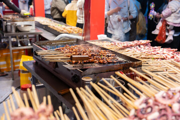Traditional Dongguan street food: grilled octopus tentacles on a barbecue grill, at a street food market in Dongguan City, Guangdong Province, China. © chuangxin