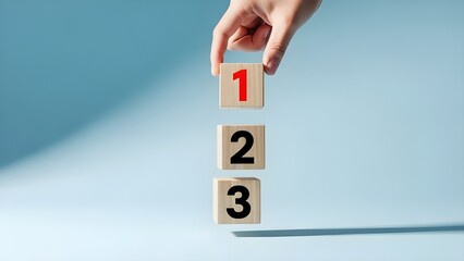 Hand picking wooden block with number one from a sequence of three blocks representing priority and steps