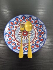 A beautifully decorated rice plate, along with a spoon.