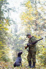 A hunter talks to his hunting dog in the autumn forest