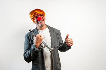 Man wearing clown wig and red nose holding trumpet giving thumbs up