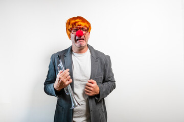 Sad clown man crying while holding a trumpet