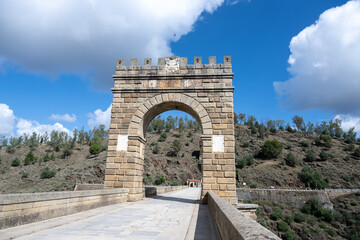 Stone arch bridge of Alcanta, Spain with castle-like structure