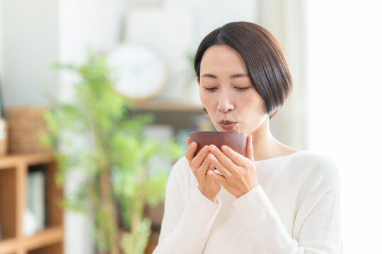 リビングで味噌汁を飲むミドルの女性