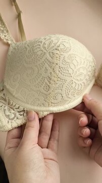 A woman shows the underwire on a beige lace bust. Women's underwear.