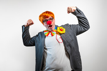 Clown performer flexing arm muscles with orange wig
