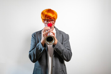Man in orange wig and clown nose playing a trumpet