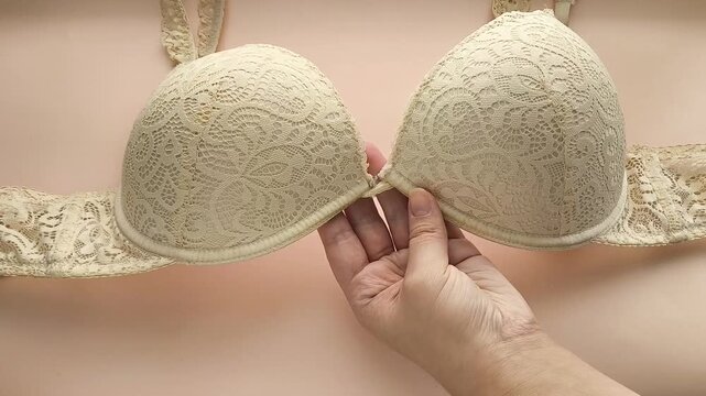 A woman shows the underwire on a beige lace bust. Women's underwear.