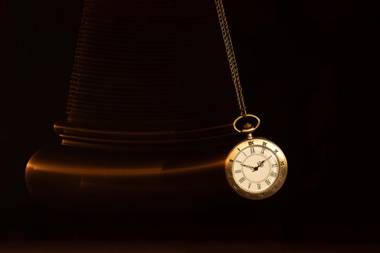 Hypnosis session. Vintage pocket watch with chain swinging over surface on dark background among faded clock faces, magic motion effect