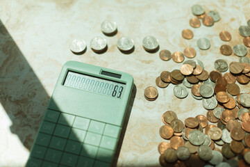 Green calculator surrounded by scattered coins