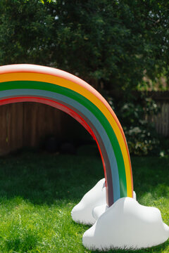 Inflatable rainbow sprinkler on green lawn during summer