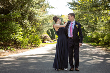 Fototapeta premium A young woman checks her dress while her date in a suit looks on