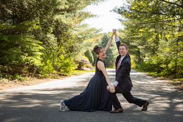 Couple in suit and dress strike an animated pose outdoors