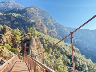 A red metal bridge over a mountain river