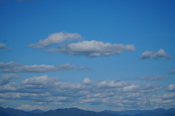 Mountain Range Under Clear Blue Sky with Soft Clouds